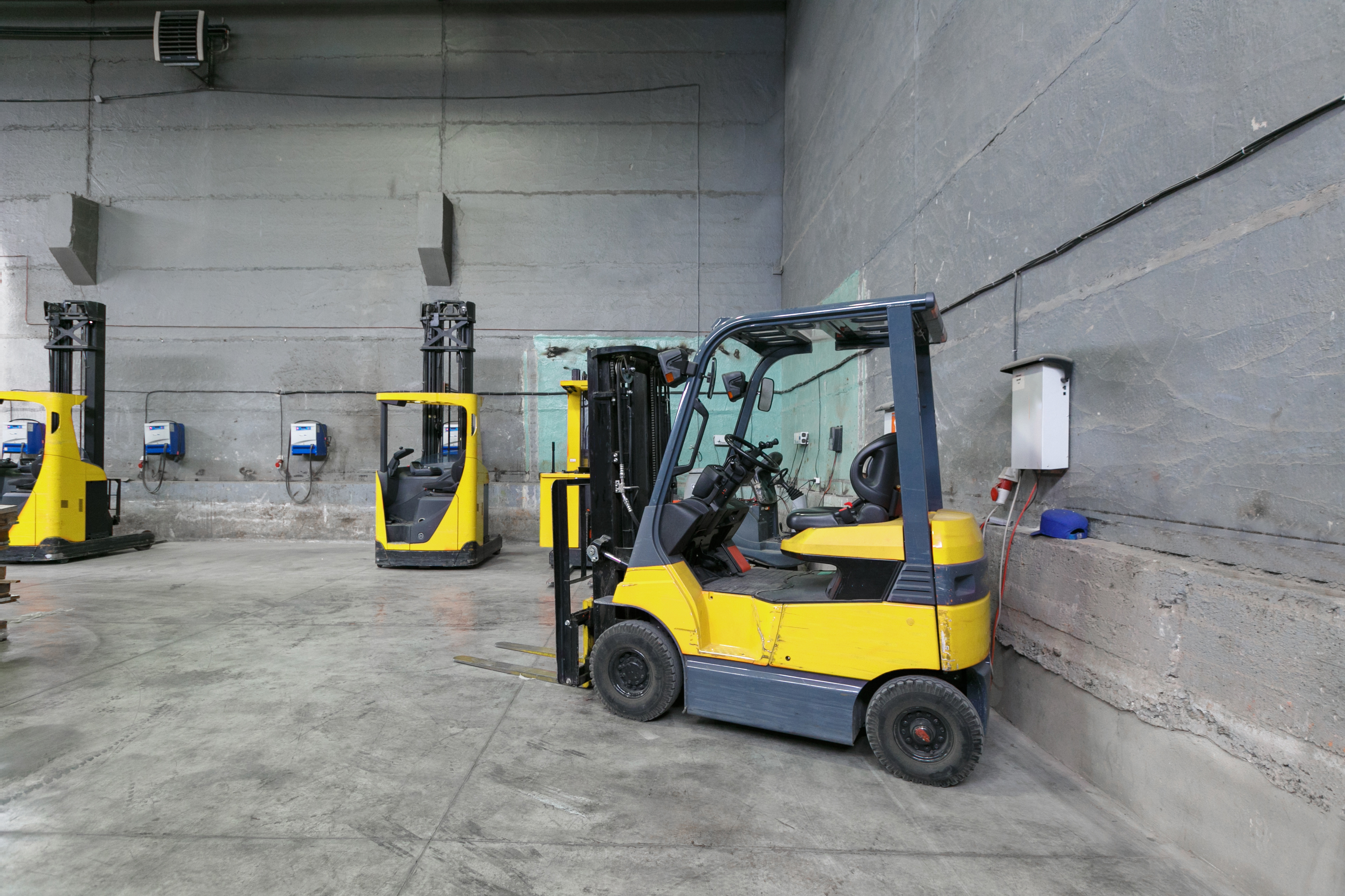 Yellow forklift charging in a warehouse